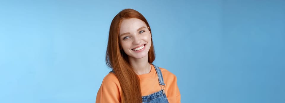 Pleasant sincere happy ginger girl blue eyes tilting head grinning happily laughing stay positive lucky spend time best friends receive praises compliments good job smiling delighted, blue background.
