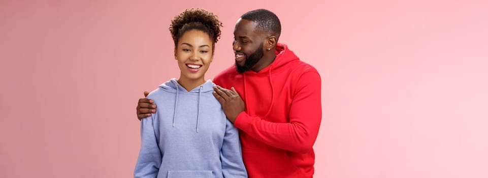 Supportive boyfriend congratulating girlfriend win first prize feel proud touching girl shoulder saying encouraging pleasant words smiling look caring lovely grinning, standing pink background.