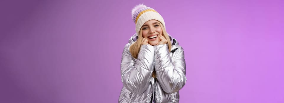 Lifestyle. Delighted charming tender female in stylish cute hat silver shiny jacket lean chin hands smiling sighing enjoying watching lovely romantic scene wanna fall in love standing happily purple background.