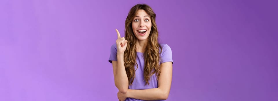 Excited cheerful happy creative smart girl raise index finger eureka gesture smiling broadly stare camera thrilled got excellent idea share suggestion think up perfect solution purple background. Lifestyle.
