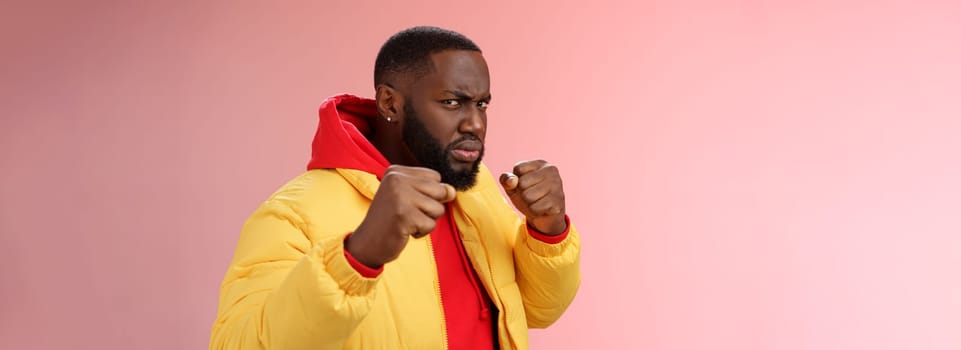 Lifestyle. Serious-looking angry irritated young black bearded man pissed rude person attidude raise fists frowning grimacing anger furious feel punch face standing boxing pose wanna fight pink background.