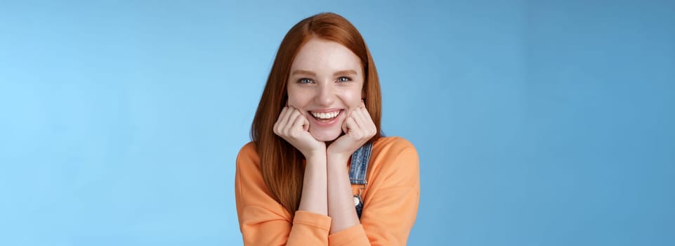 Lifestyle. Enthusiastic sassy good-looking redhead caucasian girl lean head palms look amused intrigued listen interesting story pleased smiling laughing silly jokes standing blue background excited happy.