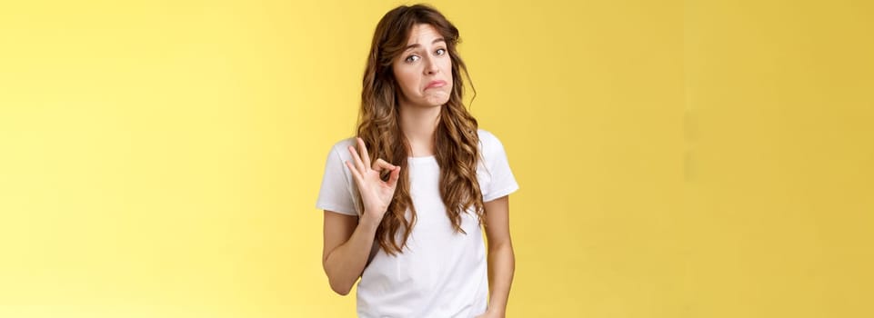 No bad actually pretty cool. Girl checks out friend design show okay ok gesture. Woman accepting excellent smooth pick-up line, nodding approval judgement stand yellow background impressed.