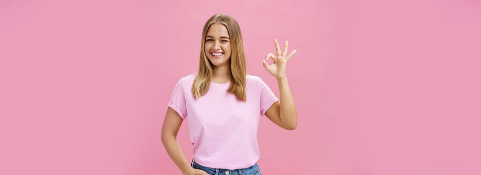 You can count on me. Portrait of confident and assertive young female shop assistant assuring product is great smiling broadly winking at camera and showing okay gesture in like and approval. Body language concept