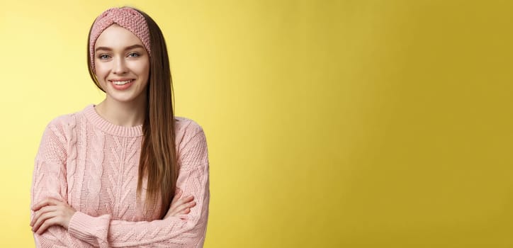 Waist-up shot of confident creative joyful cute european female model in knitted pink sweater, headband, cross arms self-assured, satisfied, smiling pleased and motivated, looking delighted.