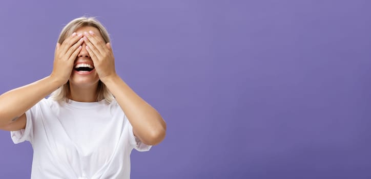 Can I look now. Portrait of excited pleased attractive tanned girlfriend in white t-shirt closing eyes and smiling broadly waiting for boyfriend bring surprising gift over purple background.