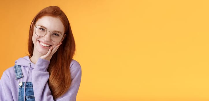Smiling satisfied happy redhead girl get rid acne delighted touching soft clean skin laughing joyfully talking feel confidence self-assured own beauty, standing orange background enjoy communication.