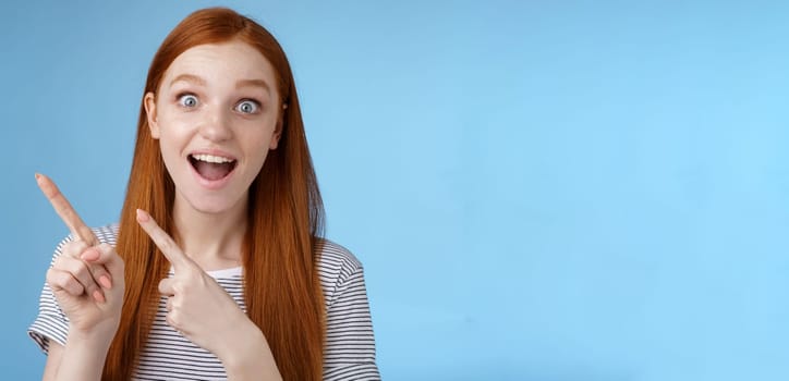 Lifestyle. Charismatic impressed surprised good-looking happy smiling cute redhead girl say wow grinning astonished wide eyes pointing upper left corner stunned thrilled speechless see awesome promo.