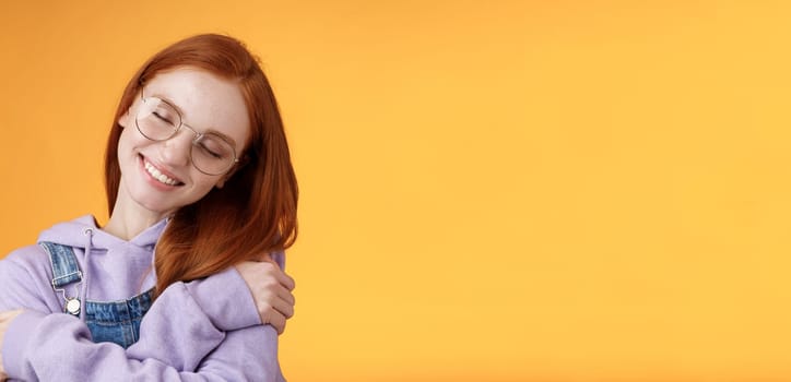 Lifestyle. Close-up romantic lovely charming redhead girl enjoy warmth love tilting head close eyes dreamy imaging perfect date hugging herself embracing own body accept body-positivity orange background.