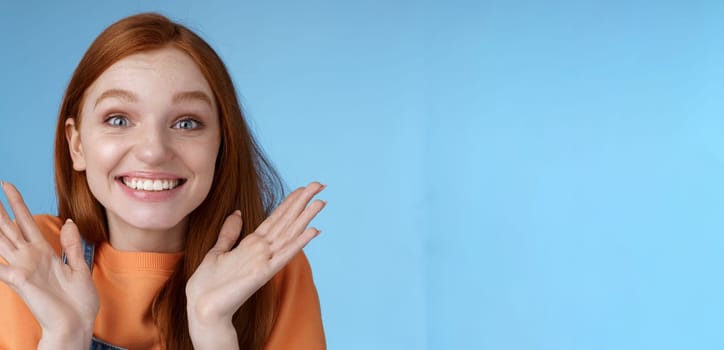 Happy rejoicing emotional young smiling redhead girl blue eyes getting exciting news grinning cheering happily raise hands thrilled wide eyes surprised accepted famous university, blue background.
