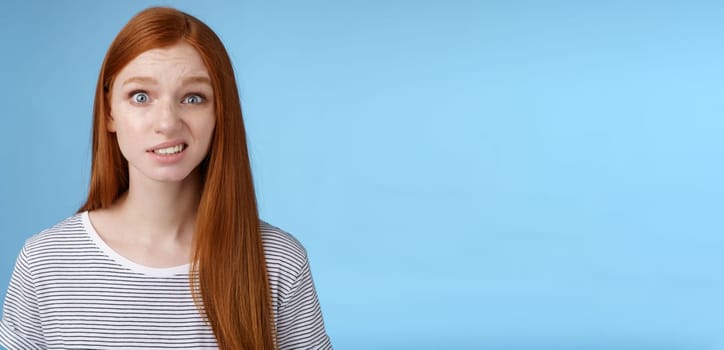 Confused stunned young doubtful redhead girl look full disbelief smirking unsure frowning cringing hesitant standing disappointed uncertain, feel awkward hearing embarrassing story. Copy space