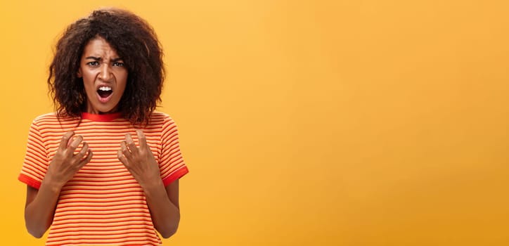 Waist-up shot of woman feeling upset feeling unfair things happened complaining and whining with regret frowning gesturing with palms near breast standing over orange background. Copy space