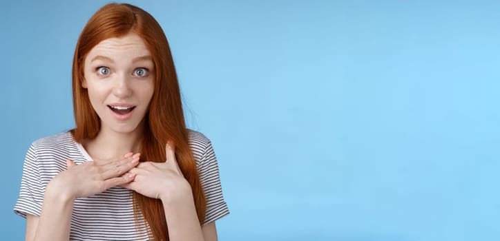 Amazed surprised young sincere redhead girl look astonished questioned gasping impressed press palms chest wide eyes stunned receive pleasant impressive gift stare gratitude touched feelings.