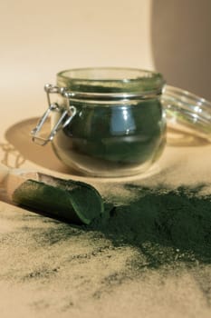 Organic blue-green algae spirulina powder food in glass jar with wooden spoon. Health benefits of spirulina chlorella. Dietary supplement superfood concept