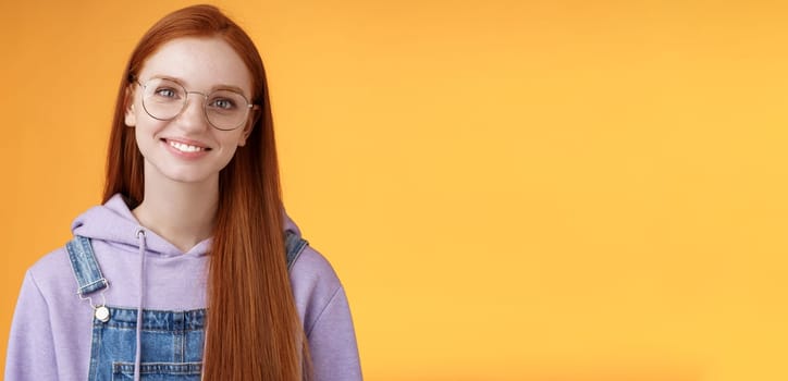 Lifestyle. Charming smart cute female freelancer order coffee working cafe standing overalls glasses hoodie smiling delighted talking casually barista orange background have happy relaxing day feel joyful.