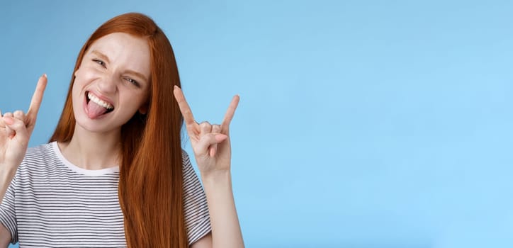 Lifestyle. Daring carefree playful excited good-looking funny redhead girl having fun show tongue squinting do thrilled grimace make rock-n-roll heavy metal sign enjoy awesome party cool concert.