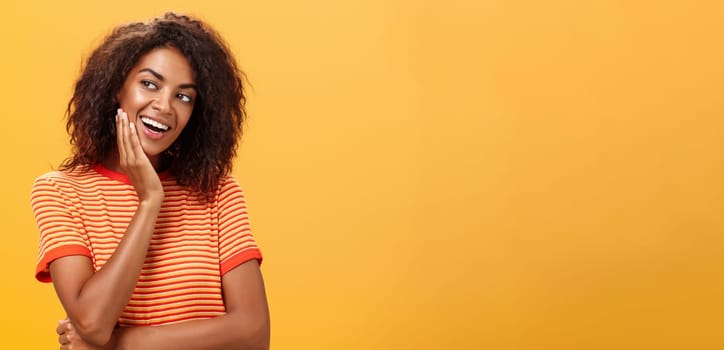 Cute creative and feminine stylish african american young female in striped t-shirt leaning head on palm gazing left with curious and adorable expression delightfully listening interesting story. Lifestyle.