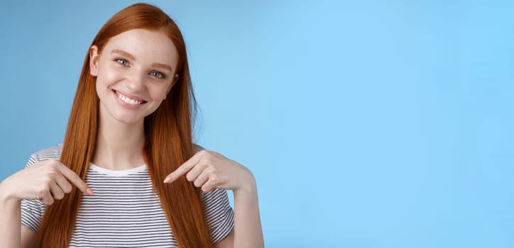 Visit place you love it. Friendly-looking kind gentle attractive redhead woman showing advertisement copy space pointing index fingers down tilting head smiling helpful recommend promo.