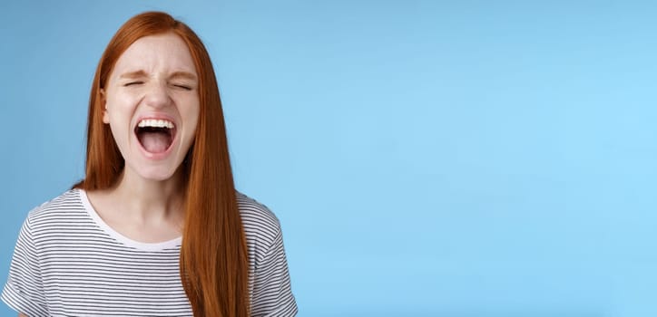 Girl screaming out loud showing attitude take out stress being fed up complaining hursh life shouting closed eyes yelling pissed standing bothered distressed blue background. Copy space