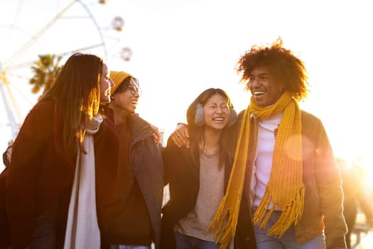 Group of friends laughing while embracing and walking together on sunny winter day in the city. Friendship and lifestyle concept.