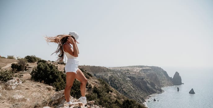 Woman travel sea. Young Happy woman in a long red dress posing on a beach near the sea on background of volcanic rocks, like in Iceland, sharing travel adventure journey