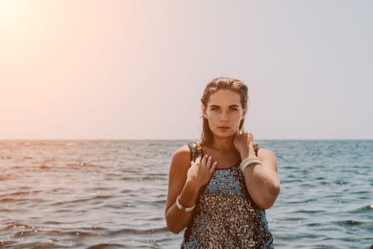 Woman travel sea. Young Happy woman in a long red dress posing on a beach near the sea on background of volcanic rocks, like in Iceland, sharing travel adventure journey