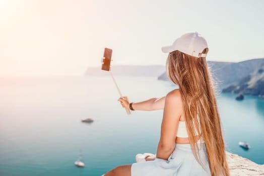 Digital nomad, Business woman working on laptop by the sea. Pretty lady typing on computer by the sea at sunset, makes a business transaction online from a distance. Freelance remote work on vacation