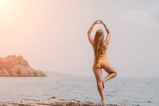 Woman meditating in yoga pose silhouette at the ocean, beach and rock mountains. Motivation and inspirational fit and exercising. Healthy lifestyle outdoors in nature, fitness concept.