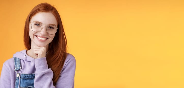 Creative outgoing young charismatic redhead female coworker discuss casual staff smiling laughing happily have pleasant conversation look camera amused tender touch chin, orange background.