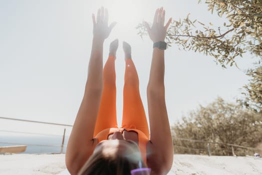 Fitness woman sea. Outdoor workout on yoga mat in park near to ocean beach. Female fitness pilates yoga routine concept. Healthy lifestyle. Happy fit woman exercising with rubber band in park.