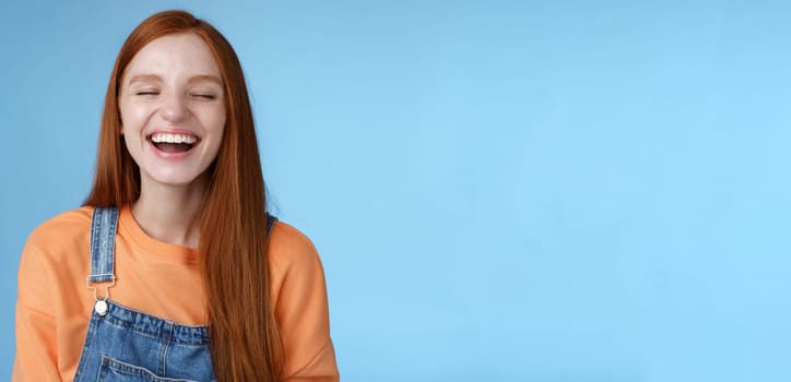 Carefree happy positive lucky redhead girl having fun close eyes smiling optimistic laughing out loud chuckling funny joke listen hilarious stories relaxing hang out friends, blue background.