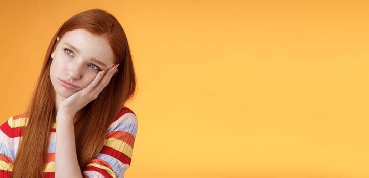 Lonely upset moody cute redhead girlfriend feeling boredom leaning palm look up pouting frowning displeased standing uneasy attend boring meeting, staring uninterested reluctant orange background.