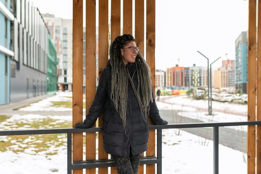 Urban charming woman with dreadlock hairstyle walks around the city at lunchtime.