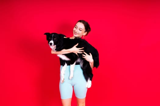 Border collie dog and sport fitness woman in front of a yellow red background