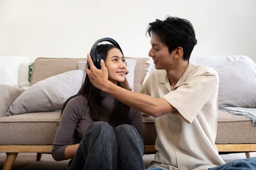 Happy couple asian young women happy playing with headphones while spending time together couch in living room at home.
