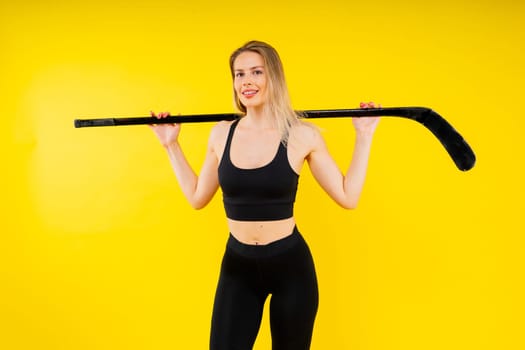 Ice hockey fan female in sports wear with hockey stick in a studio