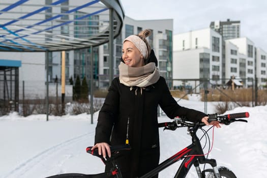 Athletic active young woman riding a bicycle on the street in winter.