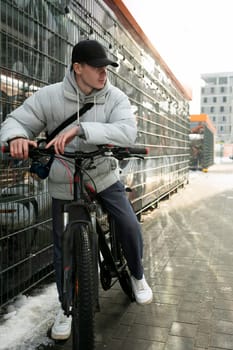 A young man in autumn clothes takes a bike ride.