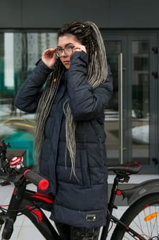 Photo on the street, a young woman took her bike for a walk in winter.