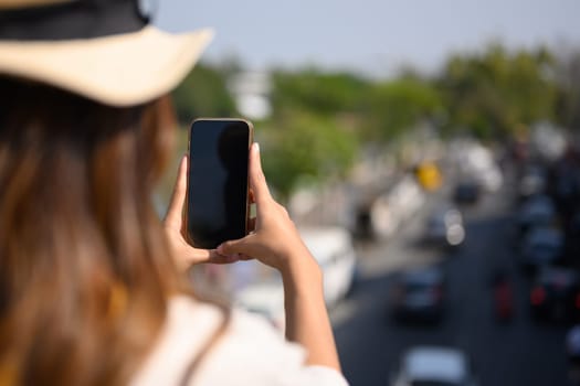 Cropped shot female tourist exploring new city and taking photo with her smart phone.