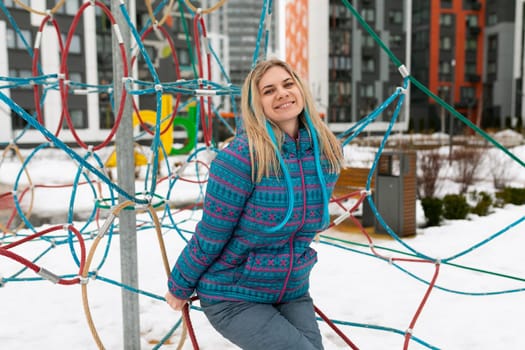 Lifestyle concept. A woman in a blue jacket walks on the playground in winter.