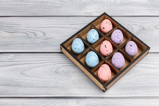 Colorful Easter eggs in a wooden box on boards. Top view.