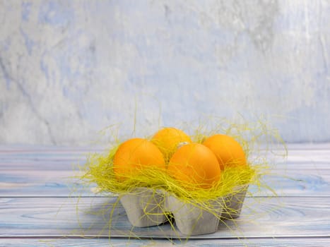 Easter eggs in a cardboard box on the wooden boards.