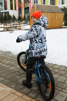A boy in winter clothes went out for a bike ride.