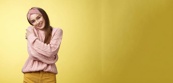 Girl feeling warm and safe thanks charming boyfriend embracing herself romantically hugging leaning on shoulder enjoying warmth of fluffy sweater, smiling tender in love over yellow background.