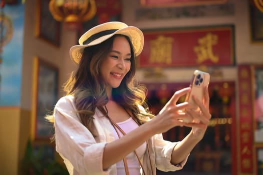 Beautiful female tourist using mobile phone while walking in China town.