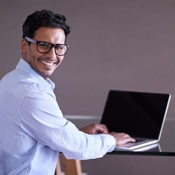 Indian businessman, smile and portrait on laptop, technology and screen in office. Happiness, eyewear and computer for entrepreneur working on project, typing and keyboard for notes and research.