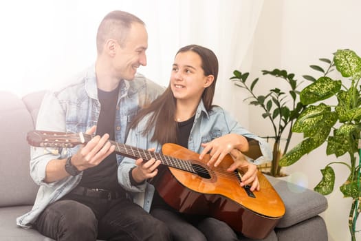 smiling father showing daughter how to play barre chord. High quality photo