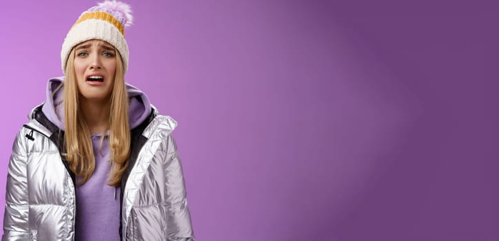 Upset sobbing miserable cute blond woman in silver stylish jacket hat crying whining unhappy feel sadness distress look disappointed complaining cruel life, unlucky standing purple background.