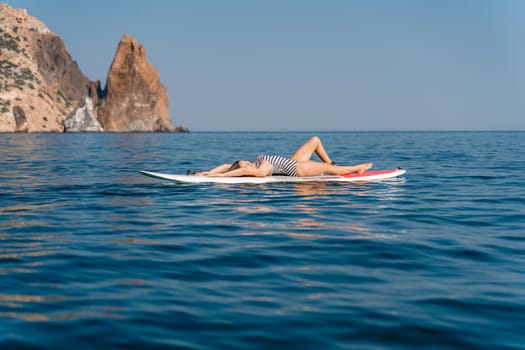 Sporty girl on a glanders surfboard in the sea on a sunny summer day. Summer activities by the sea.